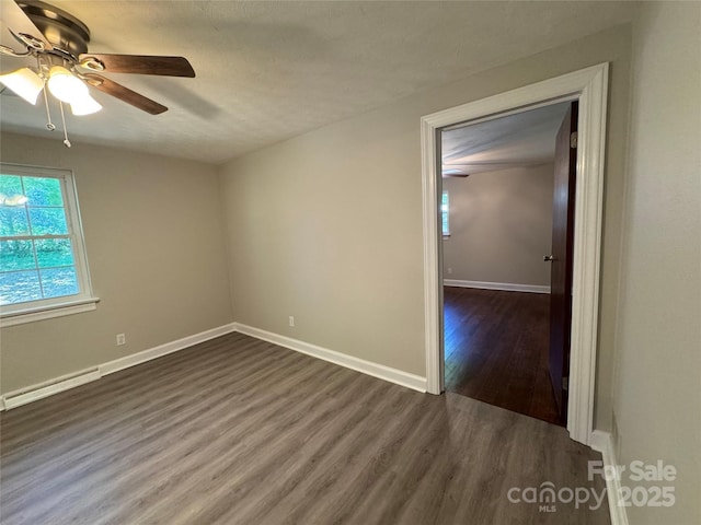 2703 34th Street Pl NE, Hickory, NC 28601 - unfurnished room featuring a baseboard heating unit, baseboards, ceiling fan, and dark wood-style flooring