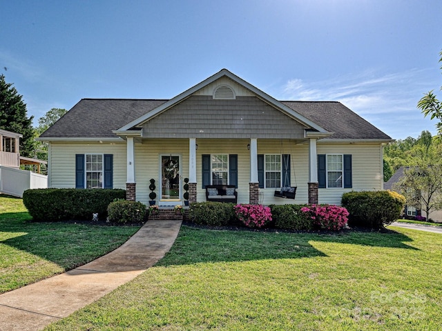 view of front of house featuring a shingled roof, a front lawn, and covered porch