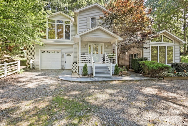view of front of house with an attached garage, fence, and gravel driveway