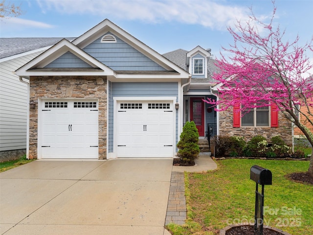 view of front of house featuring a front lawn, driveway, stone siding, an attached garage, and roof with shingles