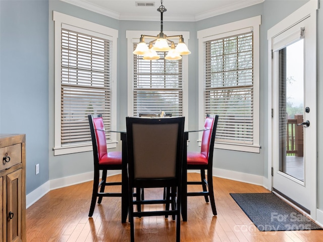 dining space featuring baseboards, a notable chandelier, wood finished floors, and crown molding