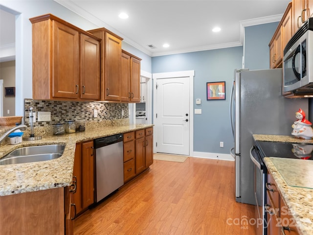 kitchen with light wood finished floors, a sink, crown molding, baseboards, and appliances with stainless steel finishes