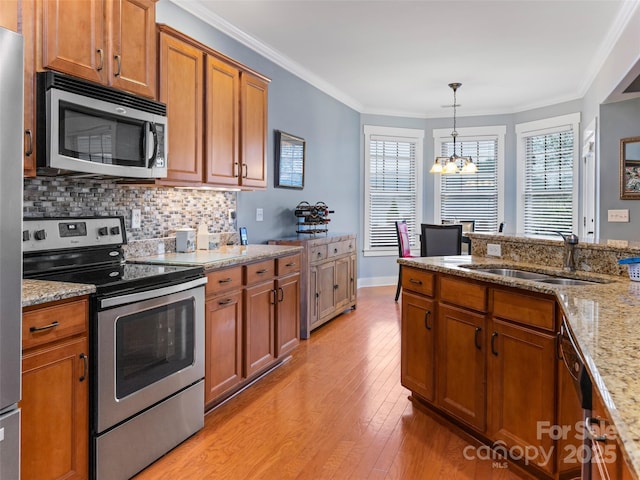 kitchen featuring light wood-style flooring, a sink, a chandelier, brown cabinets, and appliances with stainless steel finishes