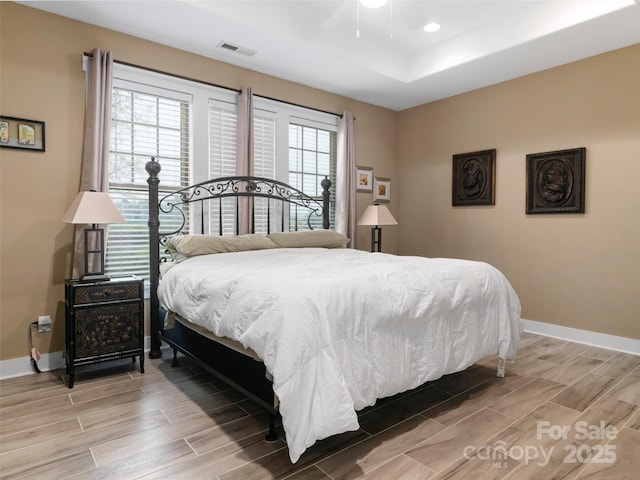 bedroom with visible vents, light wood-style flooring, baseboards, and a ceiling fan