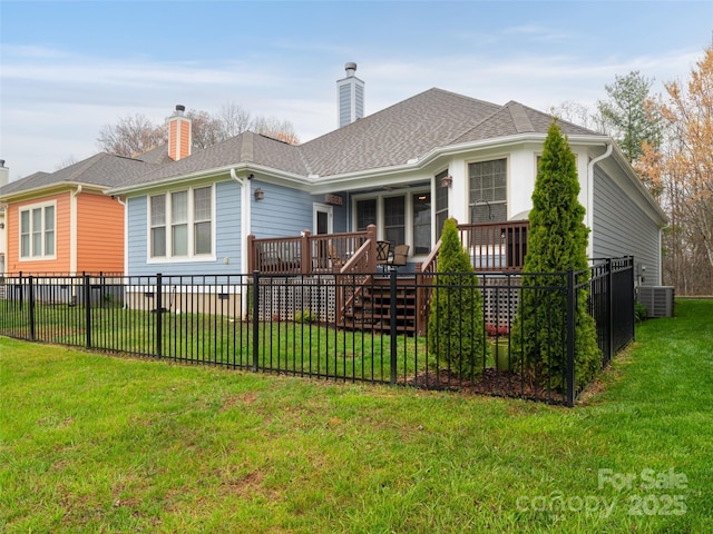 rear view of property featuring a chimney, a wooden deck, a yard, and fence private yard