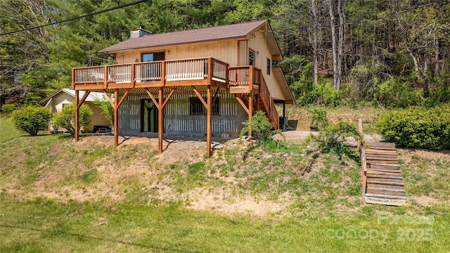 rear view of house featuring a forest view, a chimney, stairs, and a deck