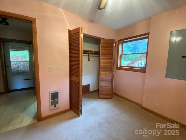 unfurnished bedroom with electric panel, heating unit, baseboards, and a closet