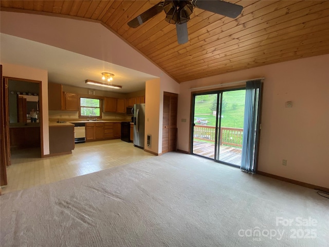 unfurnished living room featuring a ceiling fan, a sink, light carpet, baseboards, and lofted ceiling
