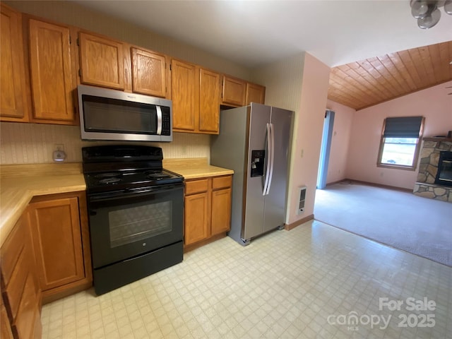 kitchen with open floor plan, brown cabinetry, appliances with stainless steel finishes, and light countertops
