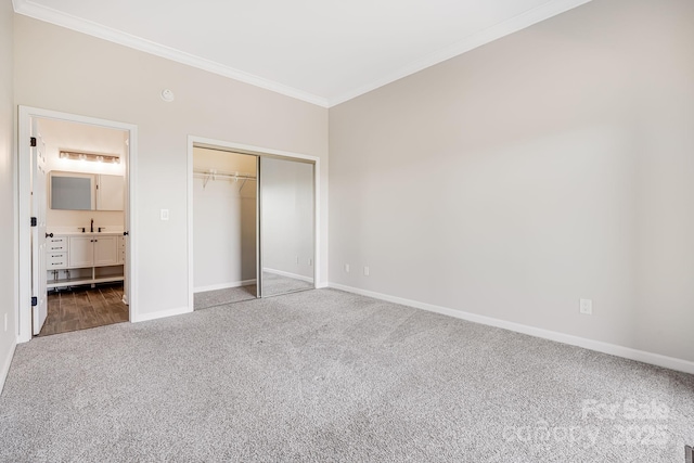 unfurnished bedroom with a sink, baseboards, carpet, a closet, and crown molding