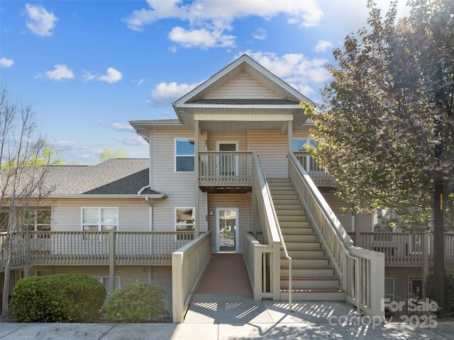 multi unit property with roof with shingles and stairs