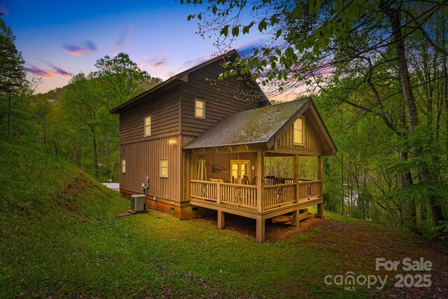 back of house at dusk with central air condition unit, a deck, and crawl space