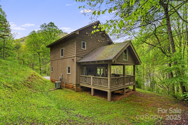 back of house featuring a wooded view, a shingled roof, central AC, and a wooden deck