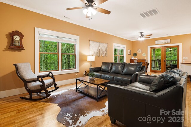 living room featuring ornamental molding, a ceiling fan, light wood-style flooring, and visible vents