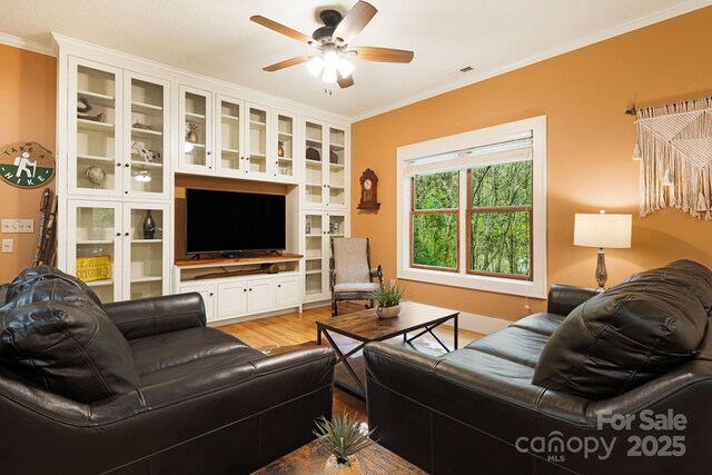 living room with crown molding, light wood-style floors, and ceiling fan