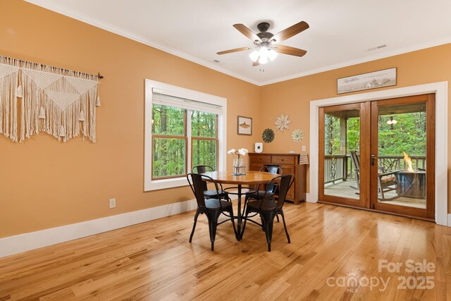 dining room featuring crown molding, french doors, light wood-style flooring, a ceiling fan, and baseboards