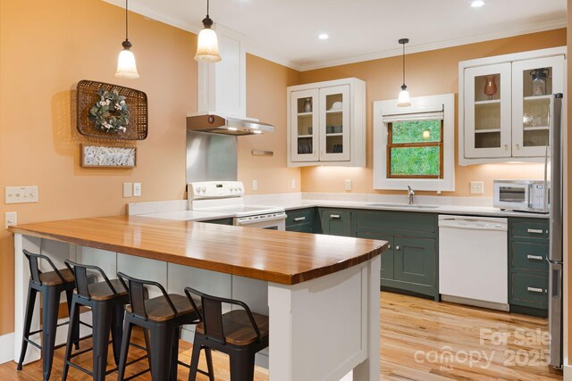 kitchen with a sink, white appliances, butcher block countertops, a peninsula, and green cabinets