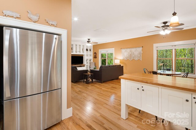 kitchen with ceiling fan, freestanding refrigerator, and white cabinetry