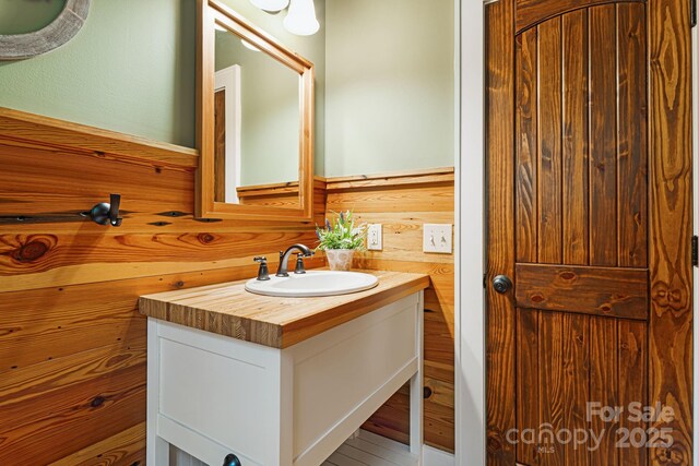 bathroom with vanity, wood walls, and a wainscoted wall