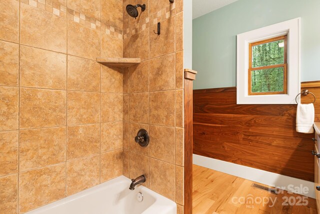 full bath with bathtub / shower combination, wood finished floors, and visible vents
