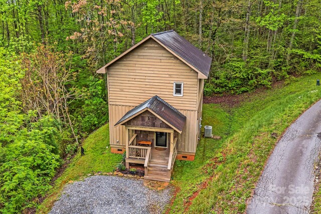 view of front facade with central AC unit and a wooded view