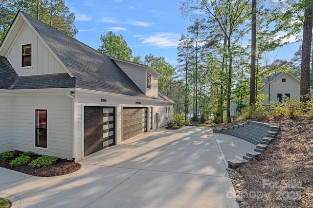 127 Holt Ln, Mooresville, NC 28117 - view of side of property with roof with shingles, an attached garage, board and batten siding, and concrete driveway