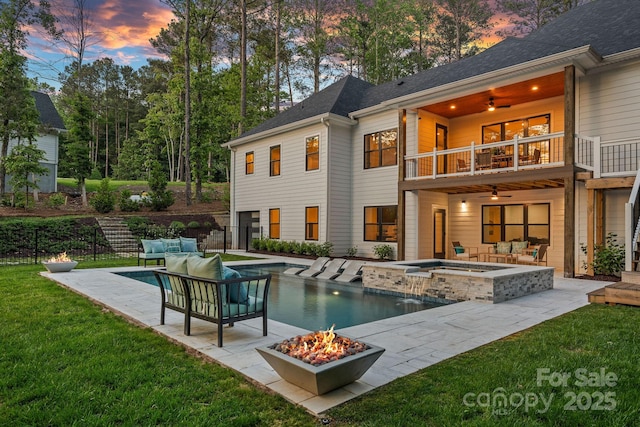 127 Holt Ln, Mooresville, NC 28117 - back of property at dusk featuring ceiling fan, an outdoor living space with a fire pit, a balcony, a lawn, and an in ground hot tub