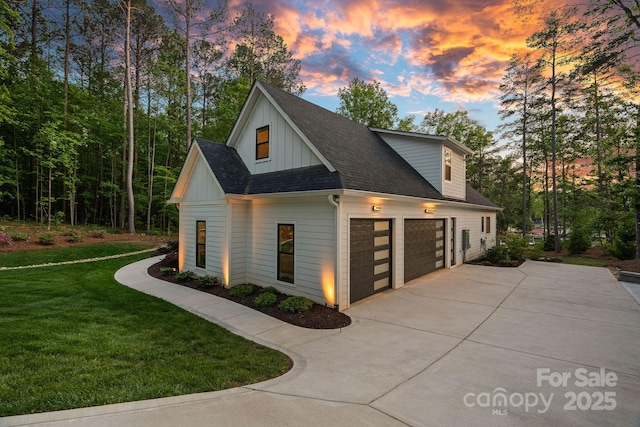 127 Holt Ln, Mooresville, NC 28117 - view of home's exterior with driveway, a shingled roof, board and batten siding, an attached garage, and a yard