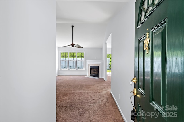 interior space featuring a tile fireplace, a high ceiling, a ceiling fan, carpet floors, and baseboards