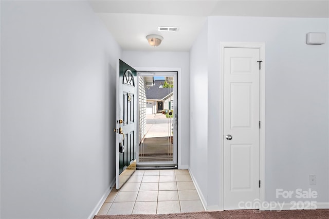 doorway with baseboards, visible vents, and light tile patterned floors