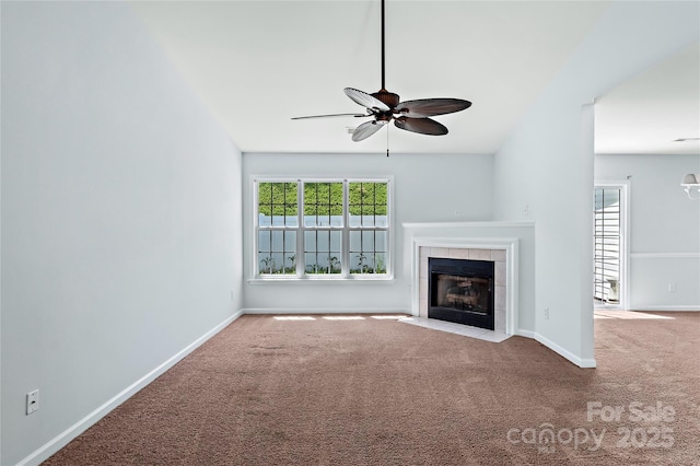 unfurnished living room with ceiling fan, baseboards, a tile fireplace, and carpet