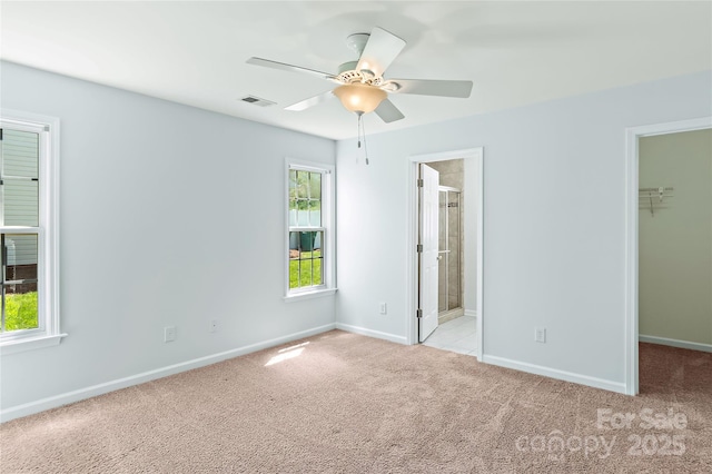unfurnished bedroom with baseboards, visible vents, a closet, carpet floors, and a walk in closet
