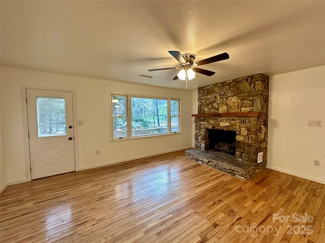 5381 State Highway 197 S Unit 3, Burnsville, NC 28714 - unfurnished living room with a stone fireplace, a ceiling fan, wood-type flooring, baseboards, and a textured ceiling