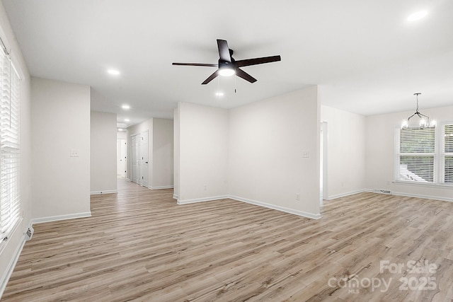empty room with recessed lighting, baseboards, light wood finished floors, and ceiling fan with notable chandelier