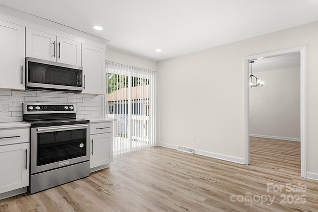 kitchen featuring light countertops, appliances with stainless steel finishes, light wood-style floors, and visible vents