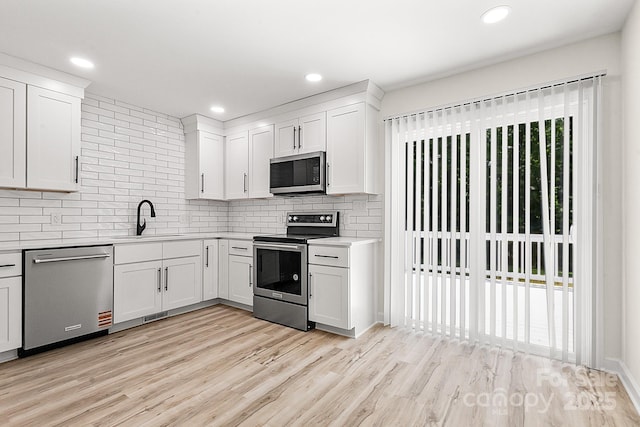 kitchen featuring light countertops, a sink, backsplash, and stainless steel appliances