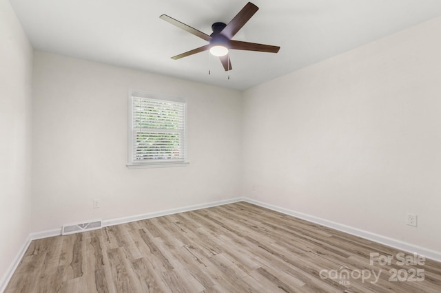 empty room with visible vents, a ceiling fan, baseboards, and wood finished floors