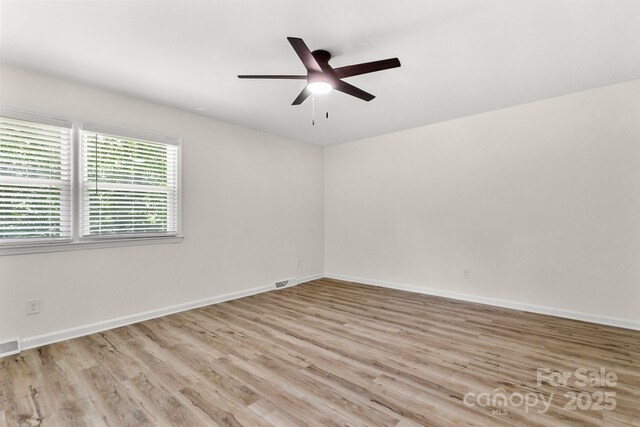 empty room with light wood-style floors, baseboards, ceiling fan, and visible vents