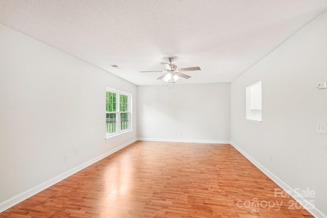 unfurnished room with baseboards, a ceiling fan, visible vents, and light wood-style flooring