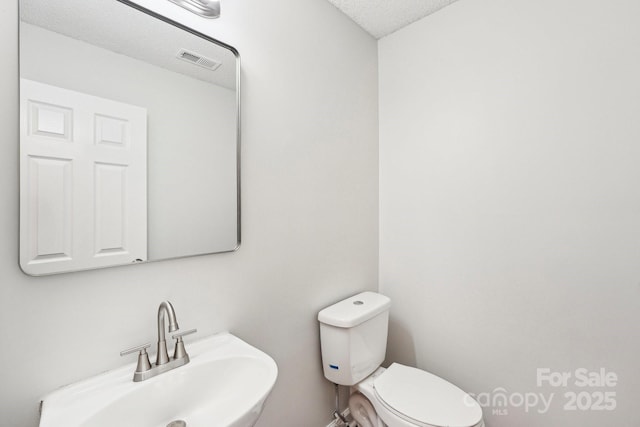 bathroom with visible vents, a sink, a textured ceiling, and toilet