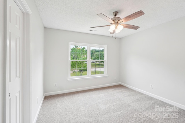 carpeted empty room with visible vents, a ceiling fan, baseboards, and a textured ceiling