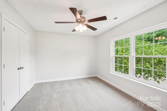 unfurnished bedroom with carpet, a textured ceiling, and baseboards