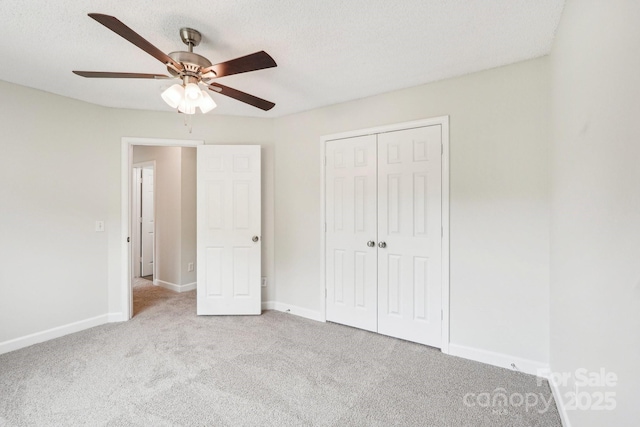 unfurnished bedroom with carpet flooring, a textured ceiling, baseboards, a ceiling fan, and a closet