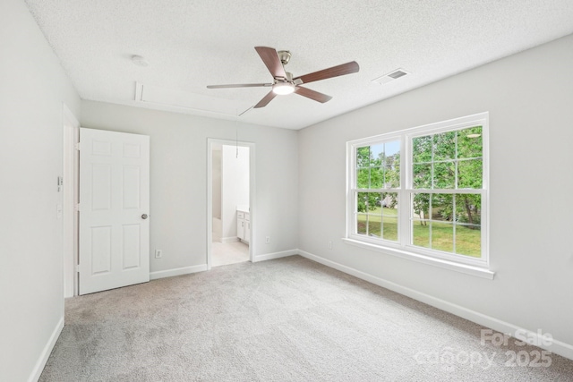 unfurnished bedroom with attic access, a textured ceiling, baseboards, visible vents, and carpet floors