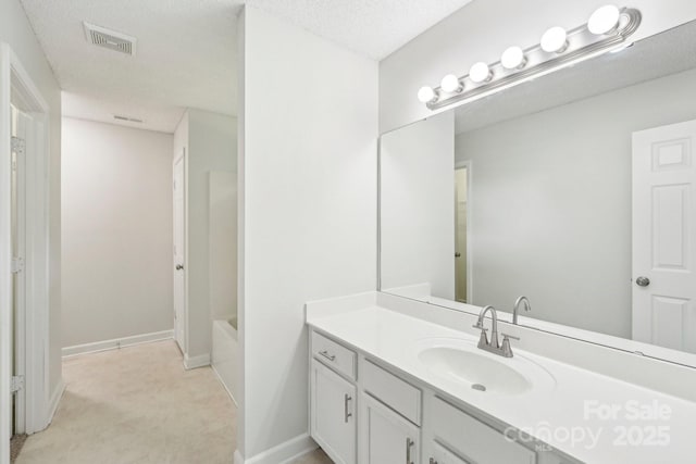 bathroom with baseboards, vanity, visible vents, and a tub