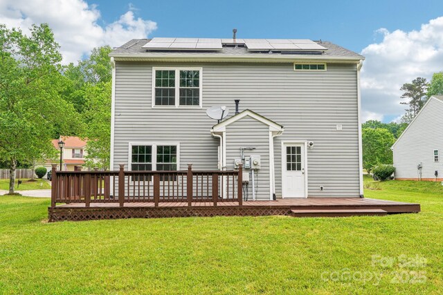 back of property featuring solar panels, a yard, and a deck