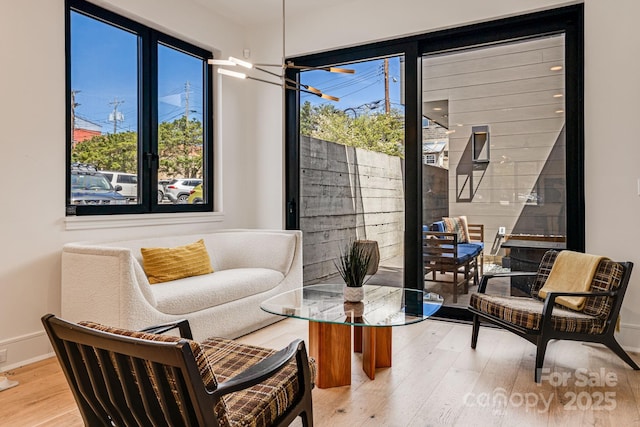sitting room with light wood-type flooring, baseboards, and a notable chandelier