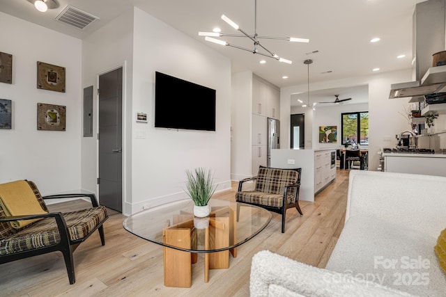 living area with light wood finished floors, electric panel, visible vents, and recessed lighting