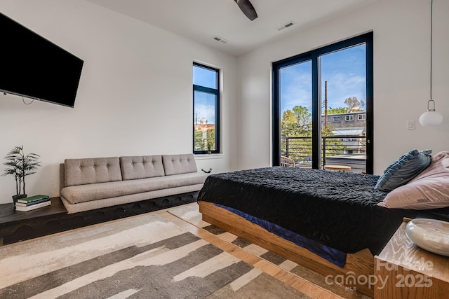 bedroom with ceiling fan, access to outside, wood finished floors, and visible vents
