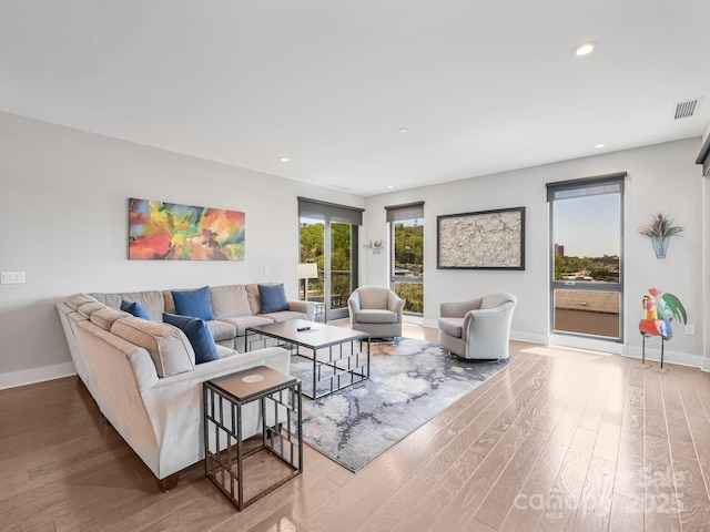 living area with recessed lighting, baseboards, visible vents, and wood finished floors